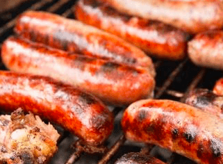 Juicy sausages sizzling on a barbecue grill.