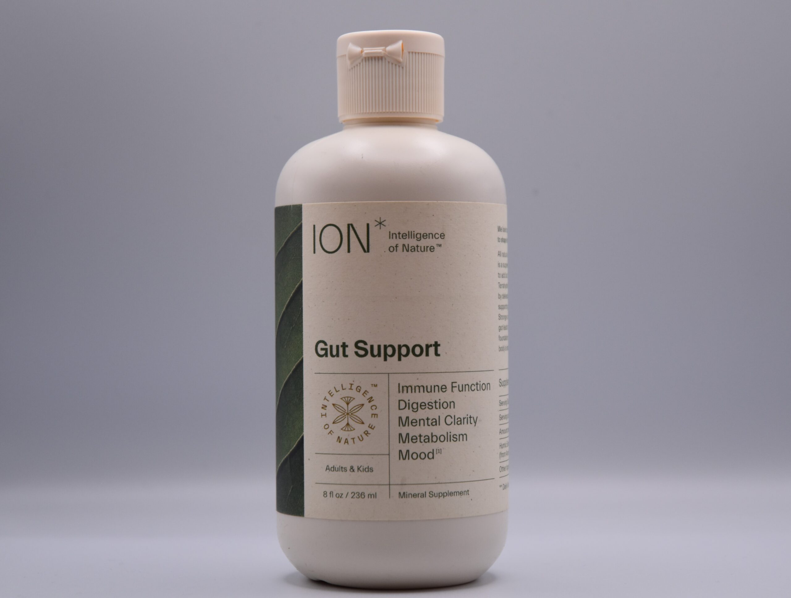 A bottle of Ion Gut Health / Restore - 8oz dietary supplement against a neutral background, highlighting its benefits for immune function, digestion, mental clarity, metabolism, and mood for both adults and kids.