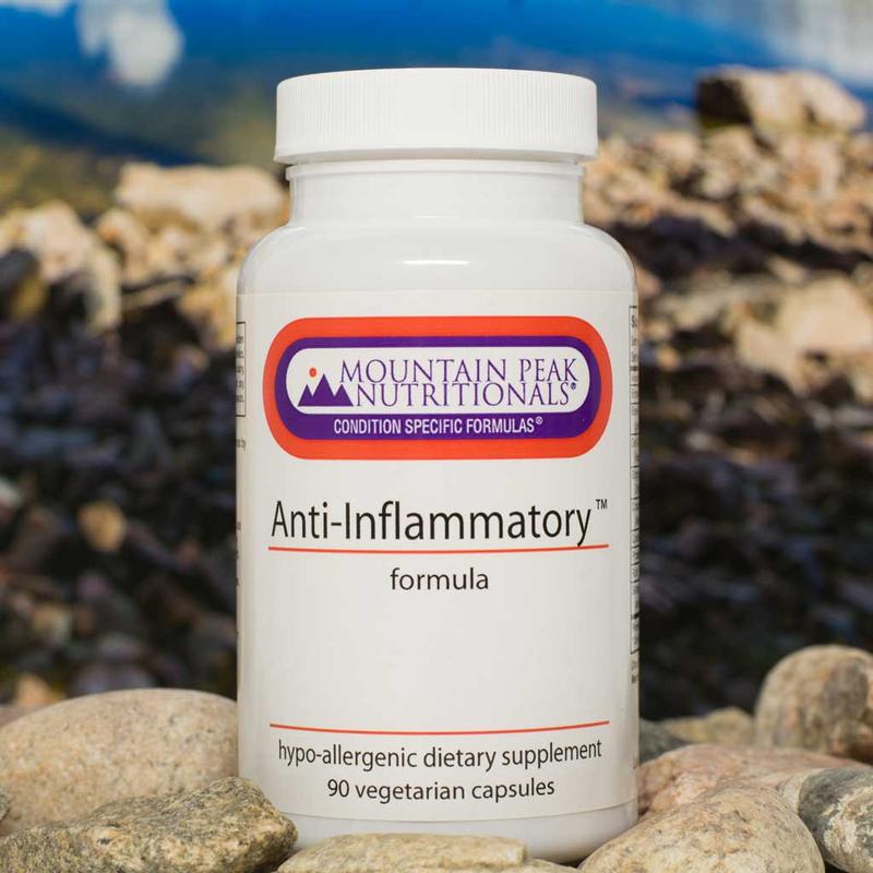 A bottle of Anti Inflammatory Formula dietary supplement from Mountain Peak Nutritionals placed on a bed of stones with a blurred natural background.