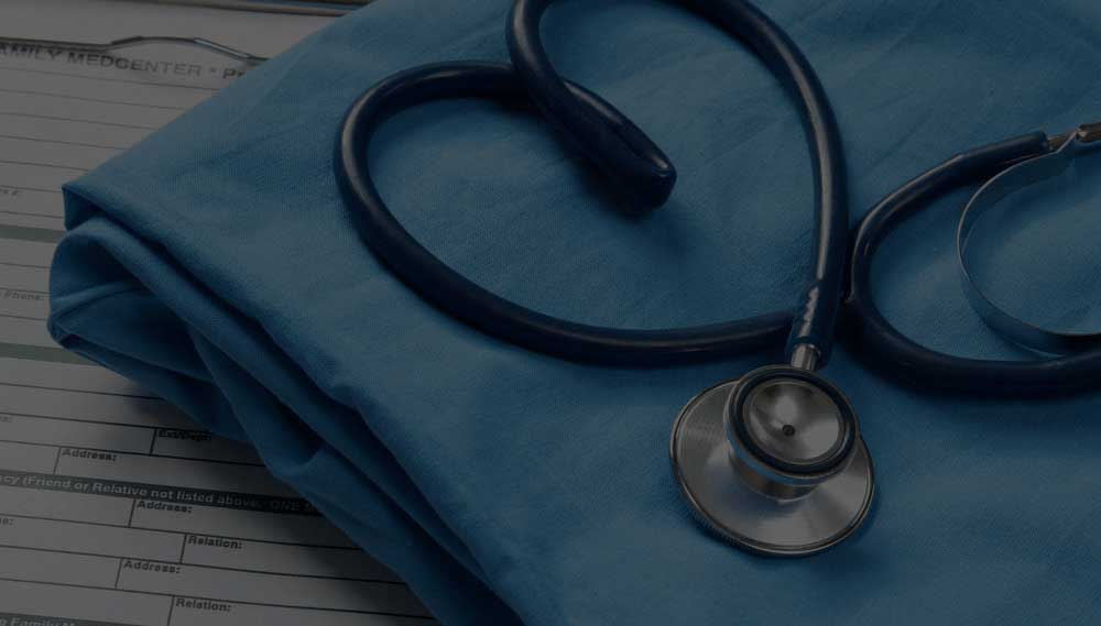 Medical professionalism: a stethoscope draped over a blue doctor's scrubs with patient paperwork in the background, symbolizing healthcare and medical practice.