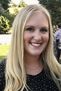 A smiling woman with long blonde hair, posing outdoors.