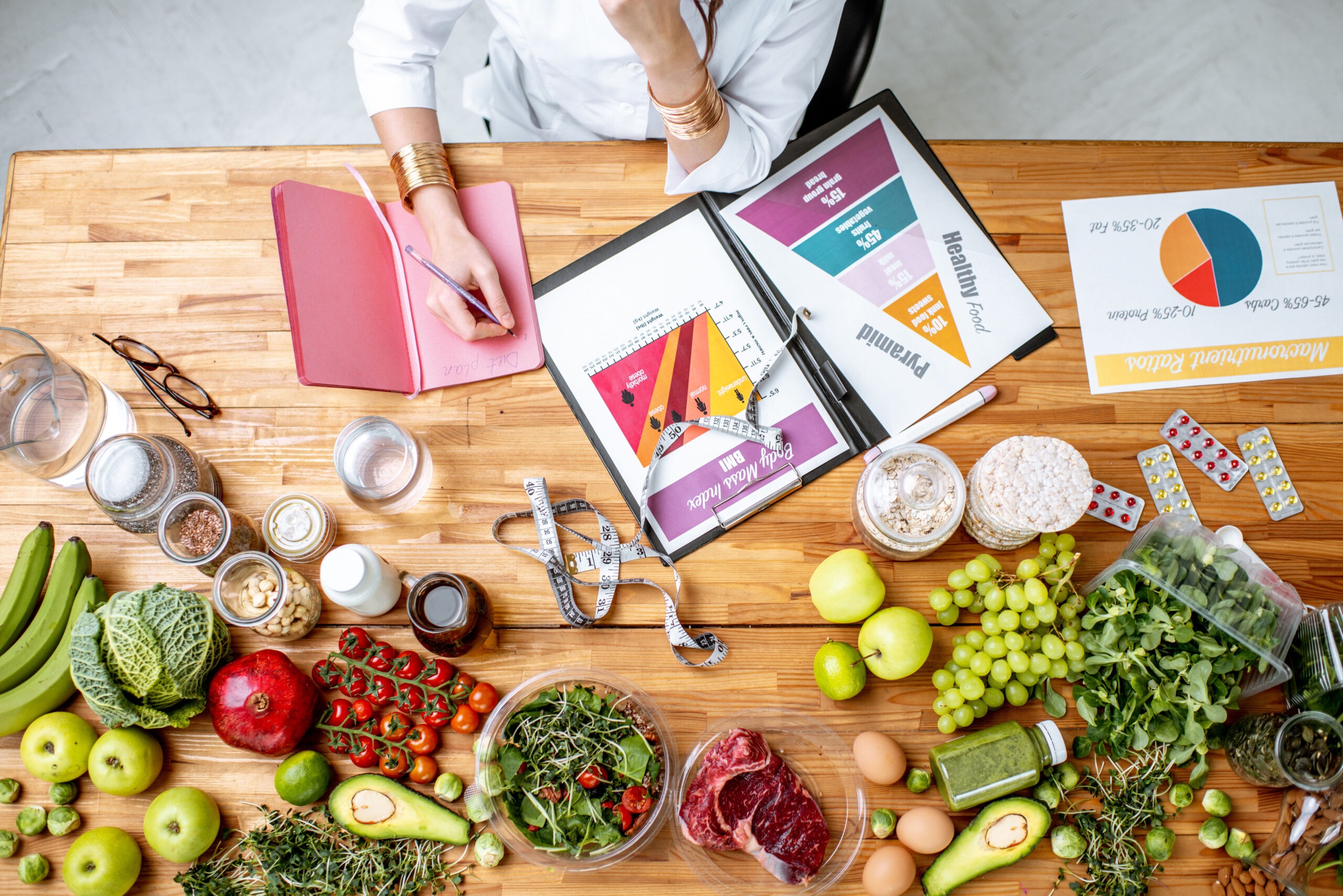 A nutritionist's desk bustling with activity, featuring a blend of healthy foods and dietary planning tools.