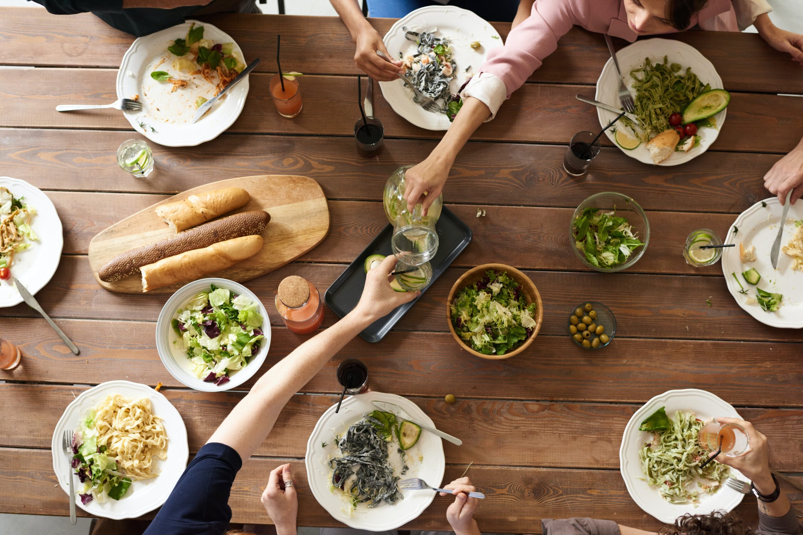 A group of people enjoying a variety of dishes at a communal table from an overhead perspective.