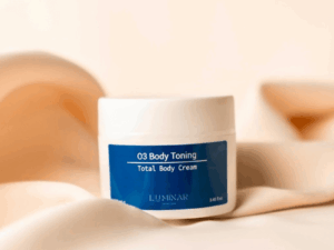 O3 Body Toning bottle on peachy silk fabric, conveying a balance of elegance and firming body care.