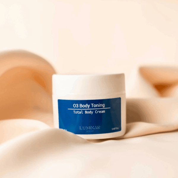O3 Body Toning bottle on peachy silk fabric, conveying a balance of elegance and firming body care.
