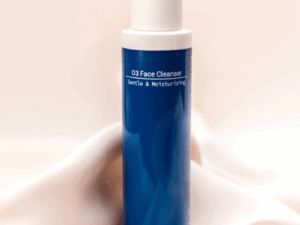O3 Face Cleanser bottle placed on peachy silk fabric, evoking a fresh, gentle start to your skincare routine with a touch of elegance.