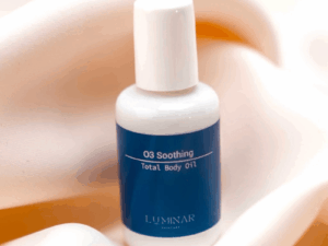 O3 Soothing Oil bottle resting on soft peachy silk fabric, evoking a sense of calm and luxury.