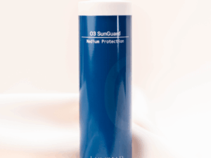 O3 Sunguard bottle resting on peachy silk fabric, combining sun protection with a soft, elegant aesthetic.