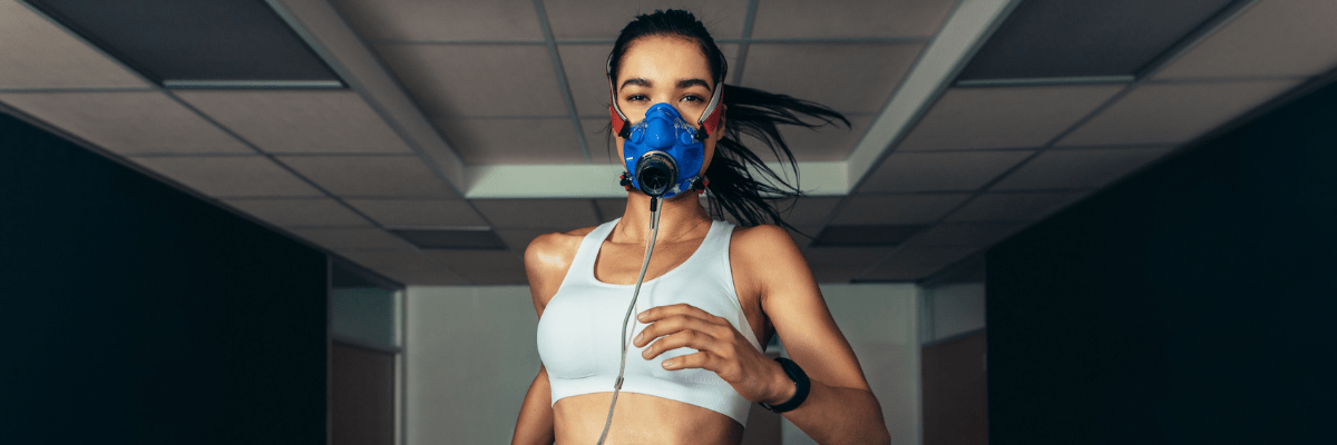 Young girl running on a treadmill while wearing the PNOE metabolic analysis mask, connected to monitoring equipment for fitness and respiratory testing.