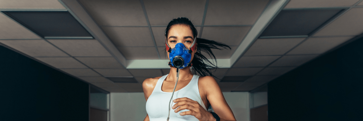 : Young girl running on a treadmill while wearing the PNOE metabolic analysis mask, connected to monitoring equipment for fitness and respiratory testing.