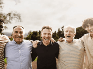 Group of smiling men of various ages standing together outdoors.