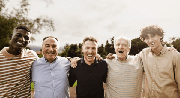 Group of smiling men of various ages standing together outdoors.