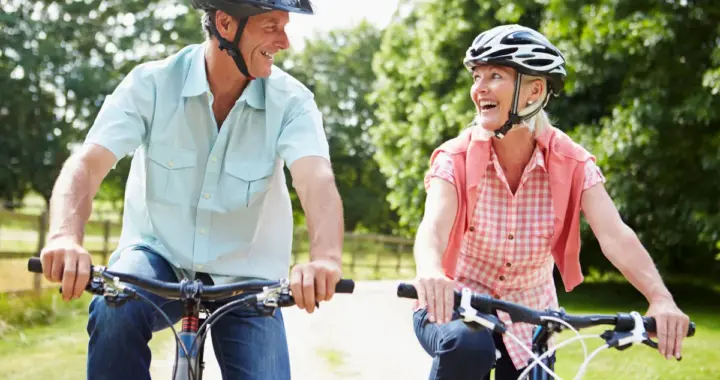 Older couple riding bicycles outdoors, representing healthy aging, active living, and overall wellness.